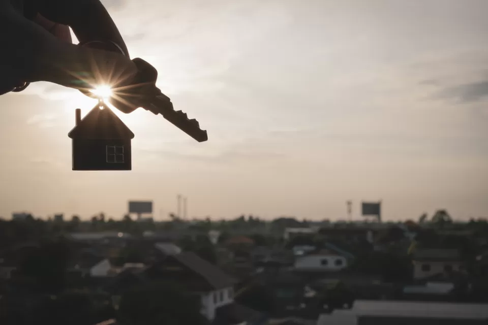 Hand holding house keys on house-shaped keychain